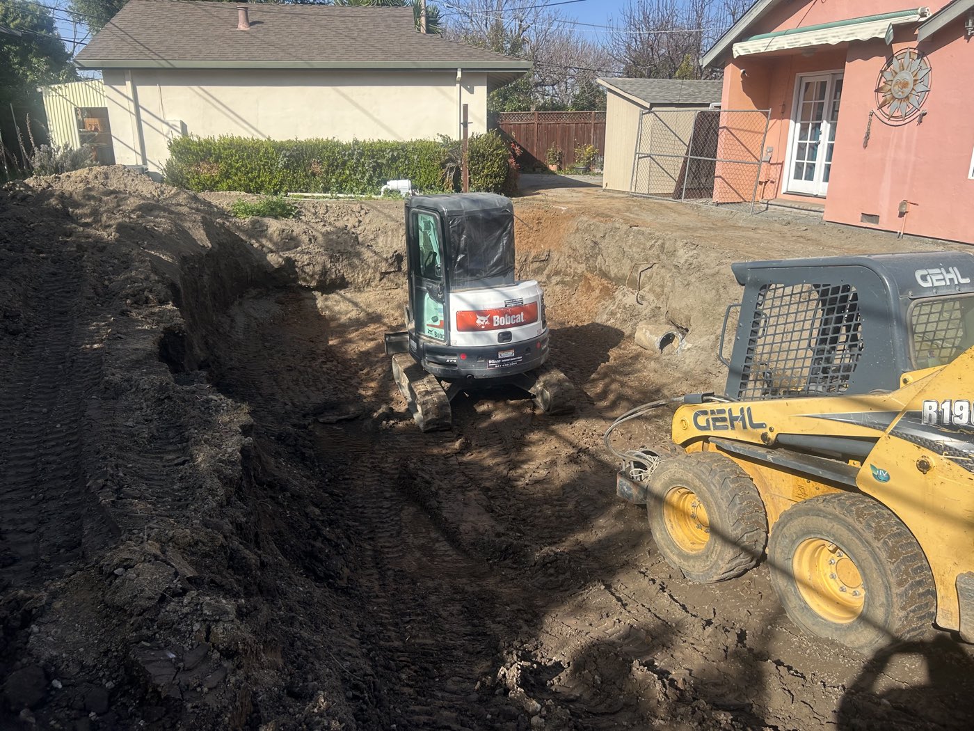 Skid steer and mini excavator digging a deep pool cavity side by side