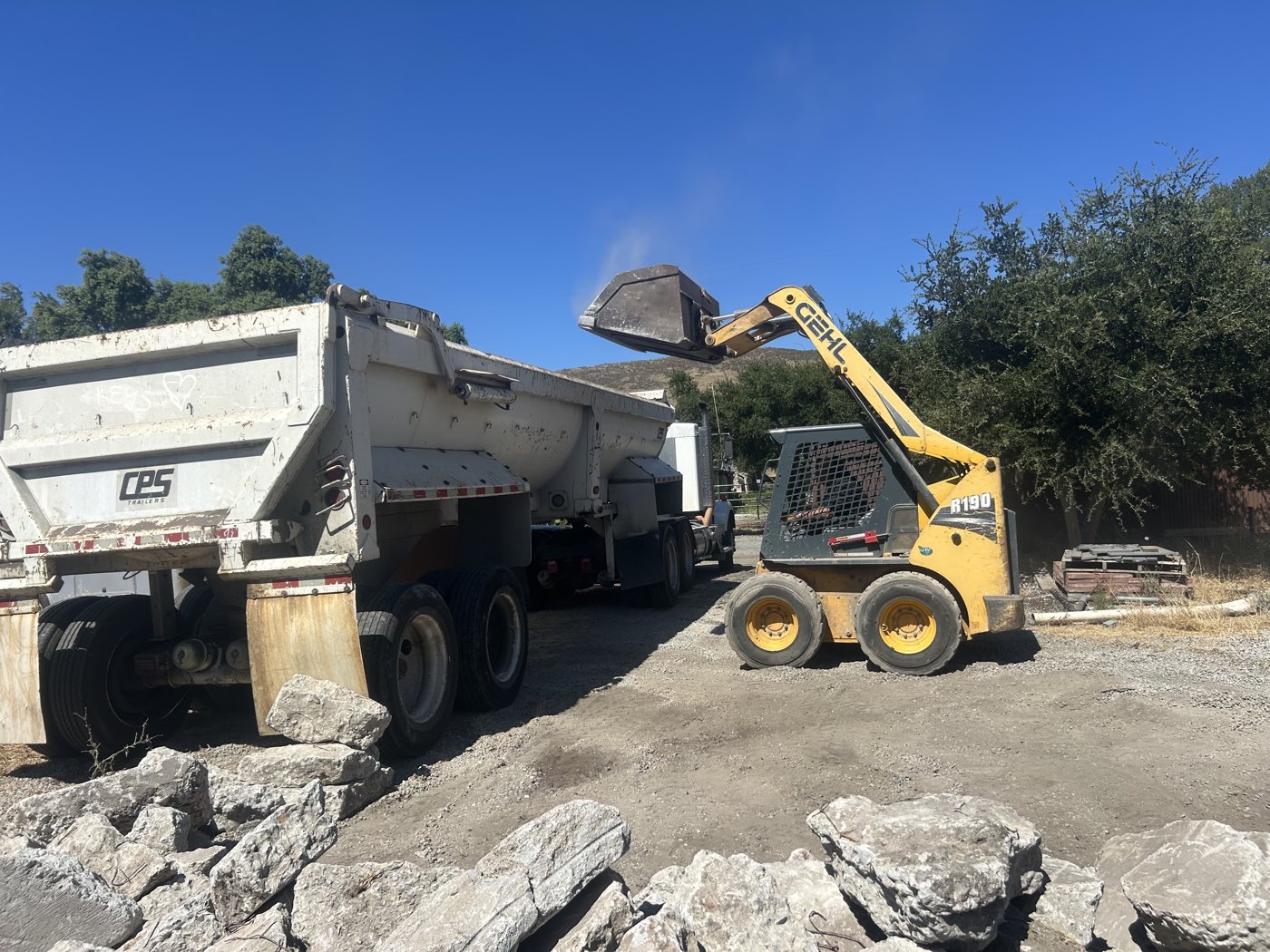 Skid-steer loading concrete rubble into a dump truck for hauling
