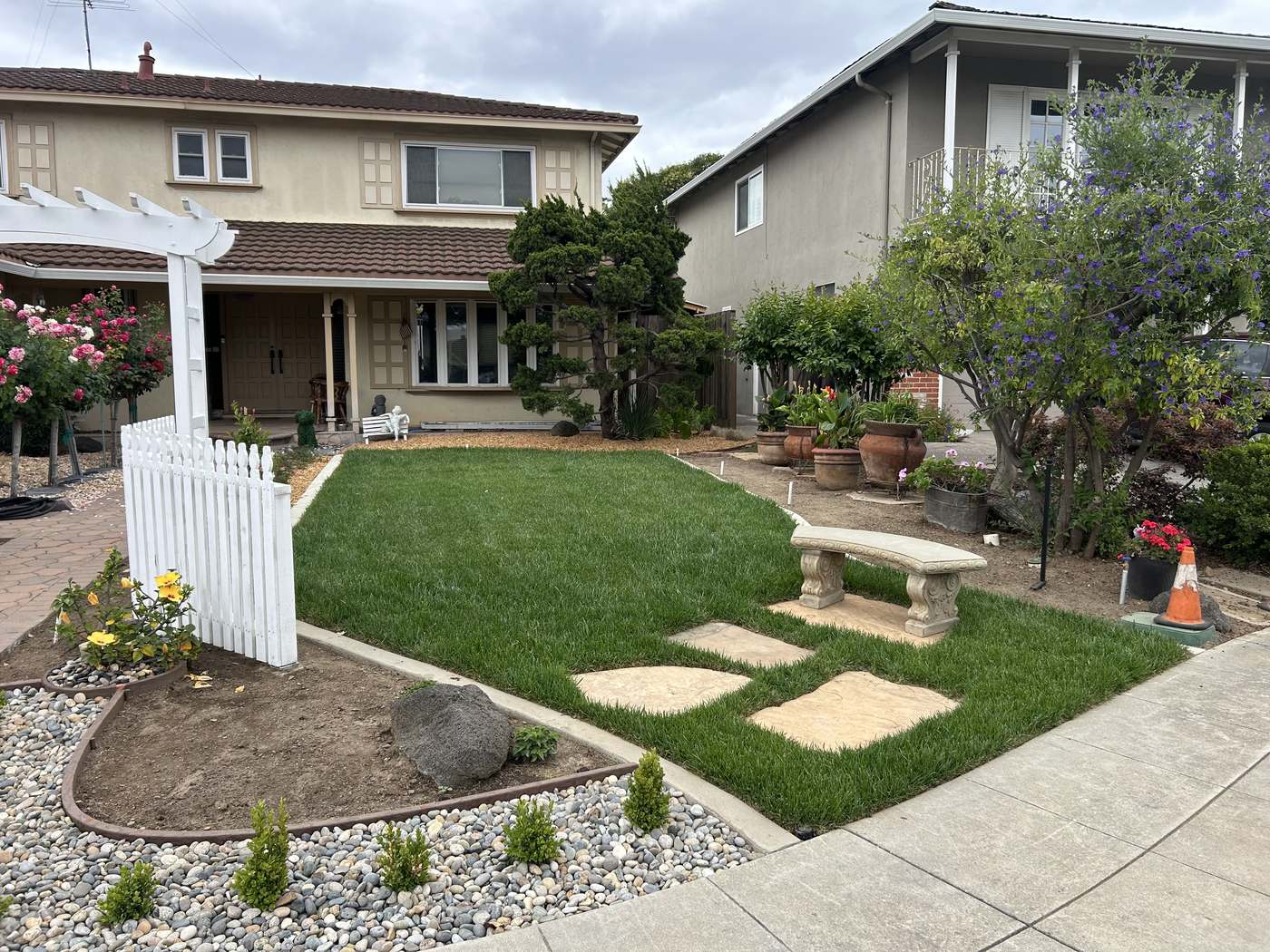 Finished front yard with new lawn, rose garden, and paver walkway after project completion