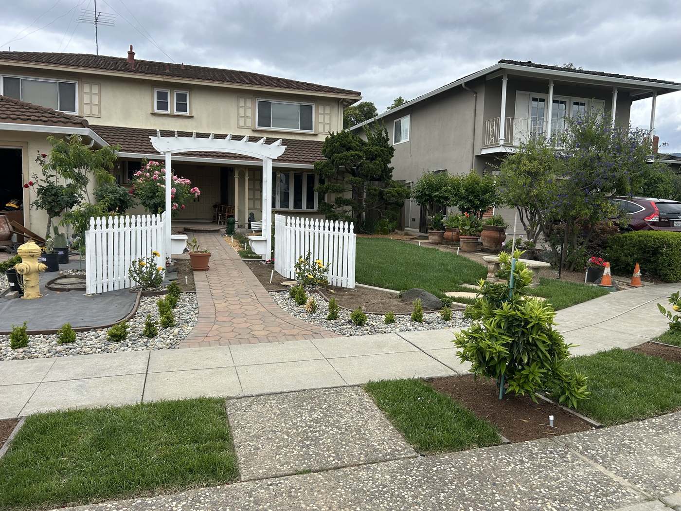Finished yard transformation with pergola, picket fence, and paver driveway