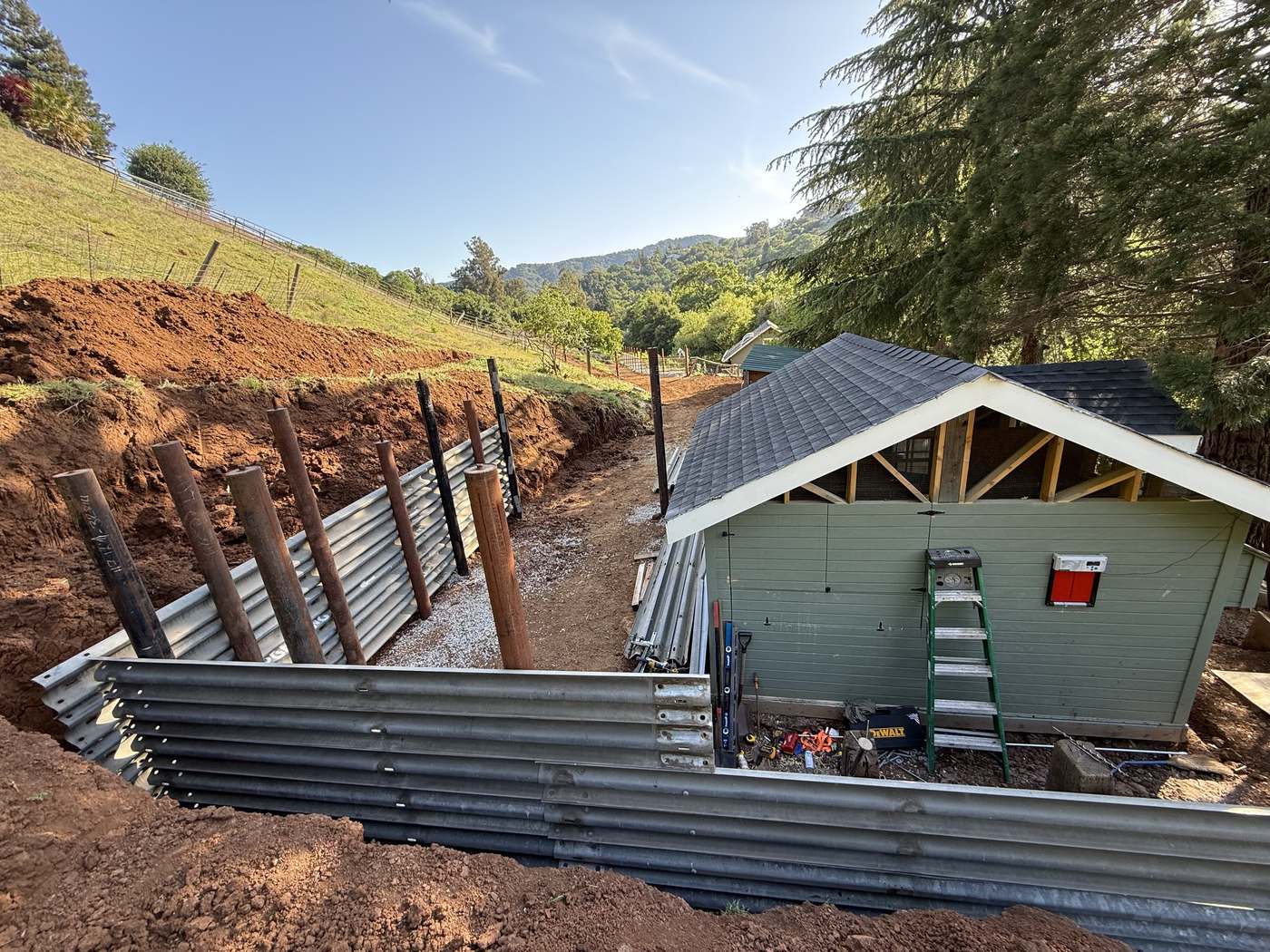 Steel I-beam retaining wall installation on a hillside property