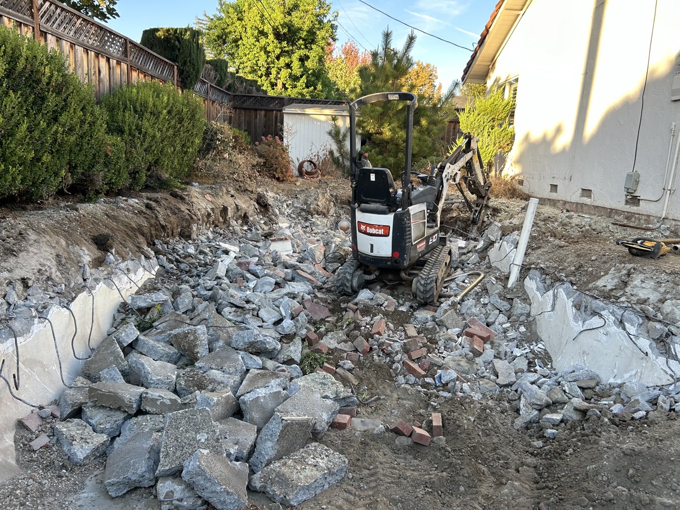 Bobcat E10 mini excavator clearing shattered concrete and brick rubble